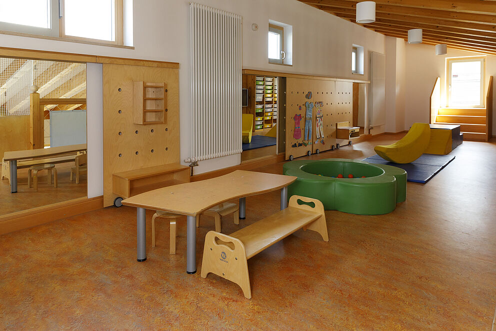 länglicher Raum mit Kindermöbeln, Bällebad und Bewegungsbereich