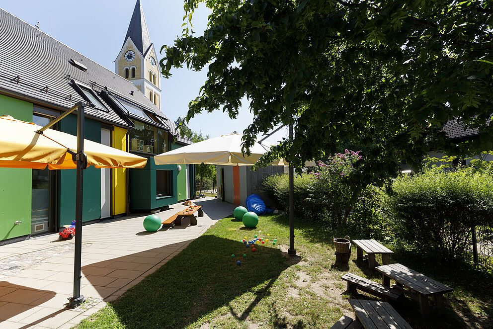 Terrasse mit Wiese, Bälle unterschiedlicher Größen und Spielmaterial auf einem Kindertisch